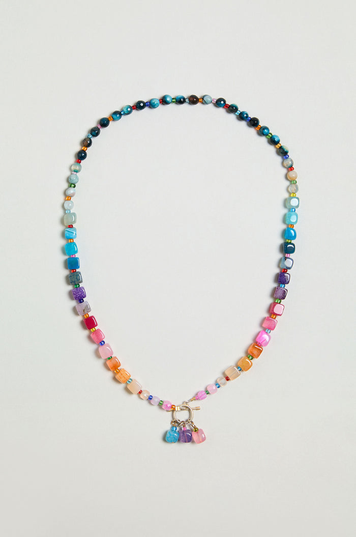 The Artisanal Rainbow Agate Toggle Necklace features multicolored agate beads in assorted shapes and sizes, accented with a cluster of vibrant charms at the center—handmade with care in Scotland.