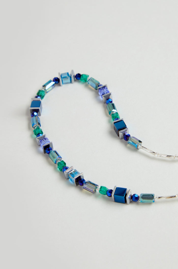 The Blue Hematite Necklace is handmade in Scotland with square and cylindrical blue, green, and silver beads plus faceted glass crystals, all arranged in a repeating pattern.