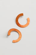 The C Curve Earrings feature a modern hoop shape in a distinctive C design, crafted from textured copper-colored metal and shown against a plain light background.