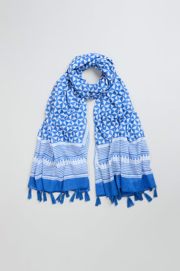 The Cobalt Tassel Cotton Scarf, featuring a bold blue and white geometric pattern and tasseled ends, is laid out flat on a light background.