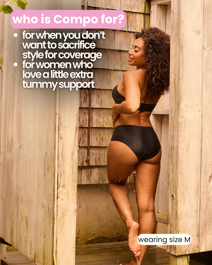 Rear view of woman wearing black Compo Hipster Bikini Bottom against wooden wall, text highlights coverage and tummy support