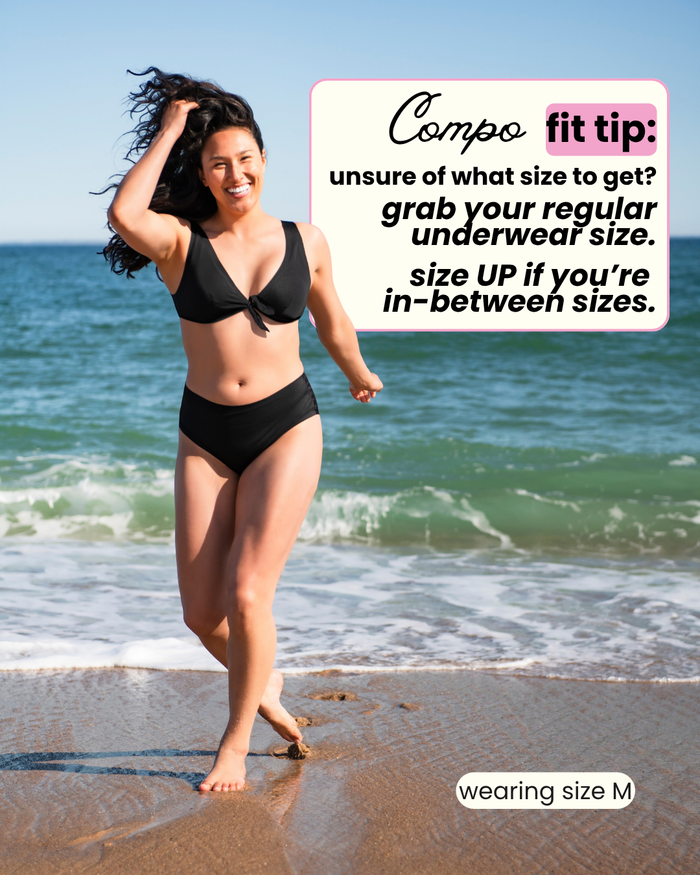 Woman in a black bikini standing on a beach with a size guide overlay.