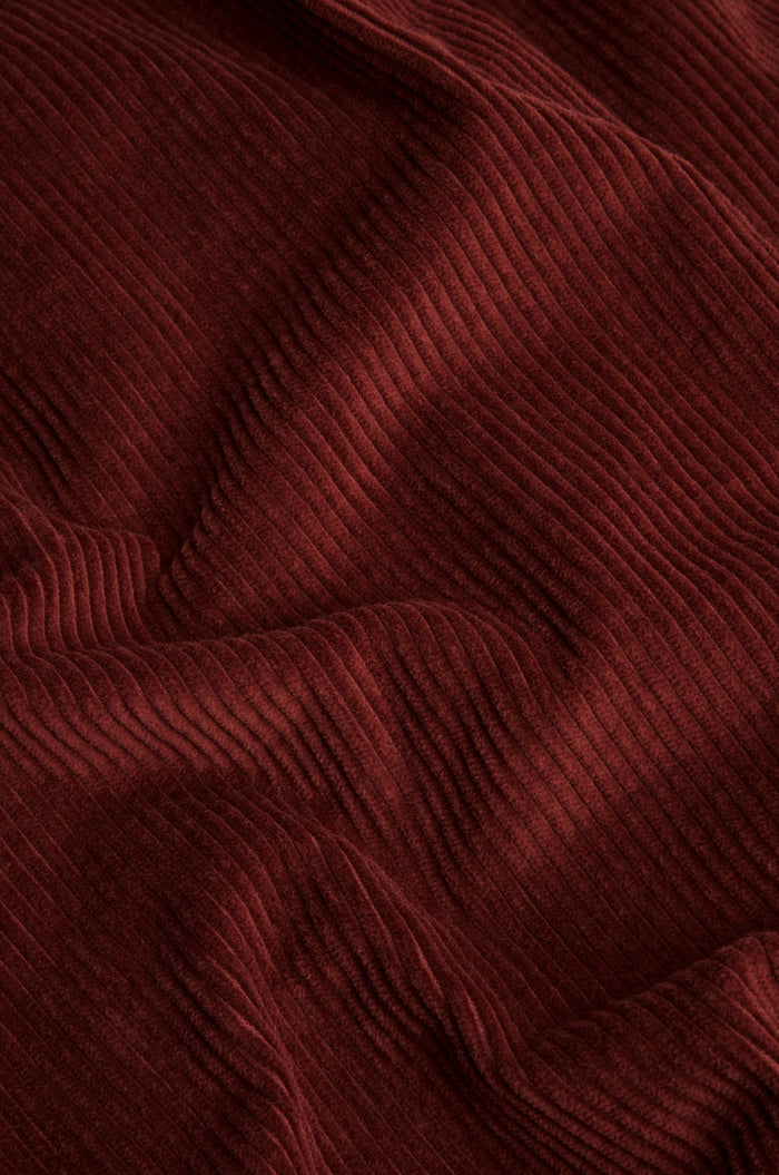 Close-up of Conker Jumbo Cord Bubble Trouser in reddish-brown, highlighting the textured vertical ridges and soft folds of its cotton corduroy fabric, characteristic of the pull-on style with a relaxed bubble silhouette.