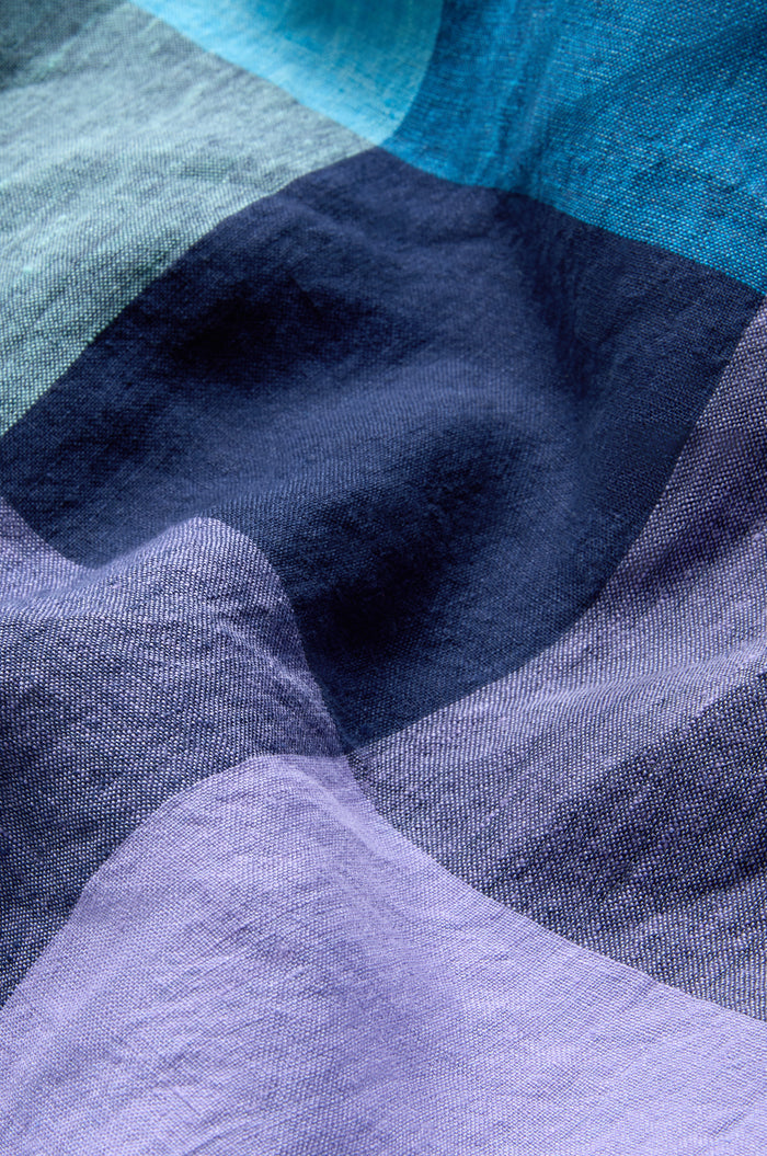 A close-up of the Cross Dye Check Linen Maxi Dress’s crumpled fabric, showing wavy, overlapping sections in blue and purple shades.