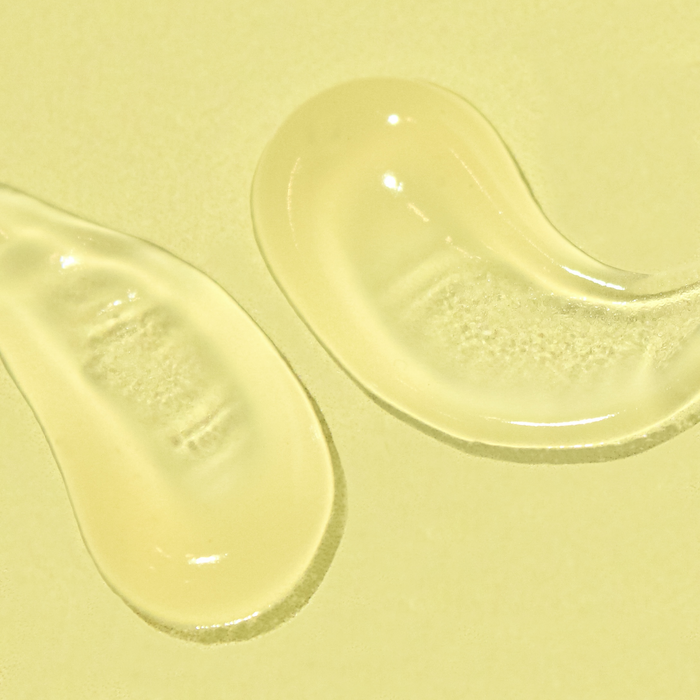 Two clear gel droplets on a pale yellow background.