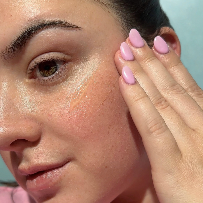 Person applying sunscreen to cheek, close-up demonstrating  application