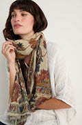 A woman wearing a white textured top and the Embroidered Tapestry Wool Scarf, featuring colorful and intricate patterns, looks to the side against a plain background.