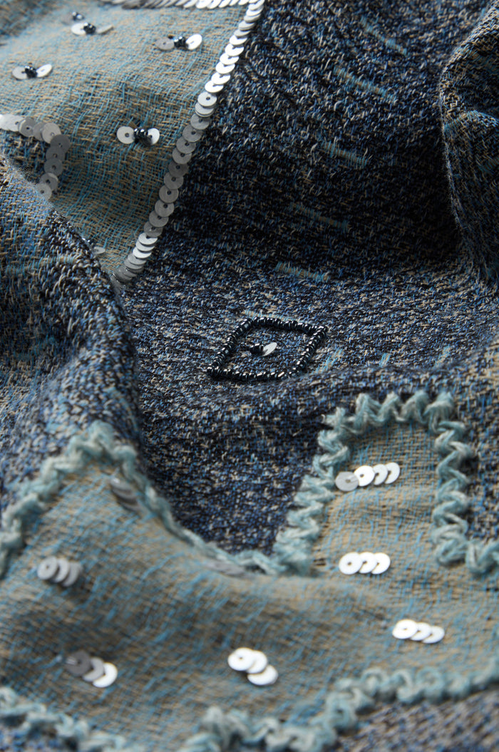 Close-up of the Etched Patchwork Sequin Wool Scarf showcasing textured blue wool with a patchwork design, embroidered patterns, a central diamond motif, and patches outlined in sequin accents and zigzag stitching.