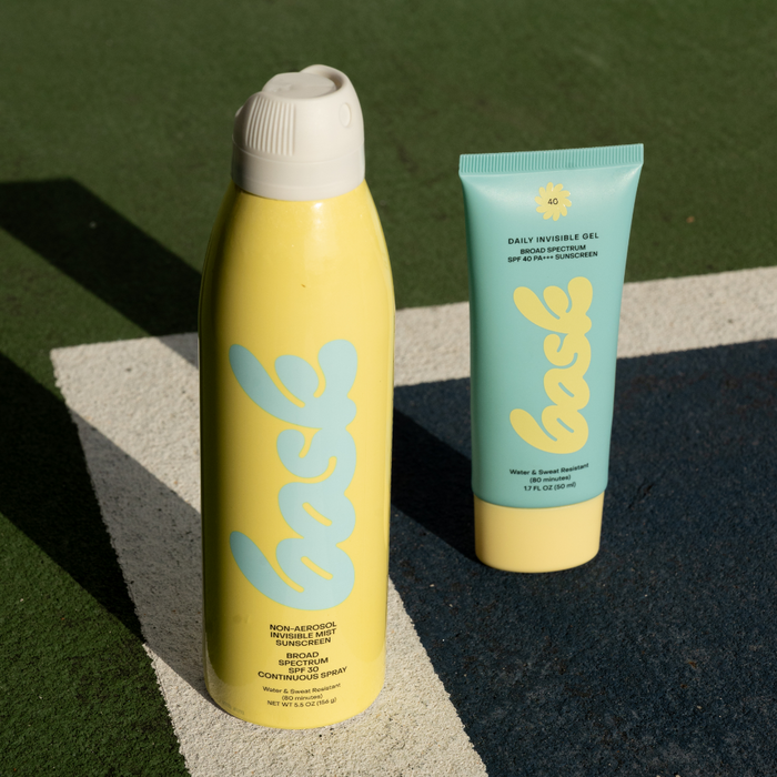 Front view of Feel Good Bundle showcasing 5.5 ounce SPF 30 spray and 1.7 ounce SPF 40 daily invisible gel on green and white surface