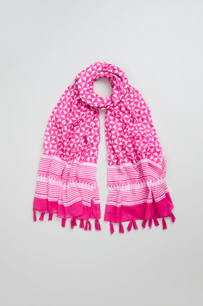 A Fuchsia Tassel Cotton Scarf featuring a bold geometric print and delicate tassel edging is laid out on a light gray background.