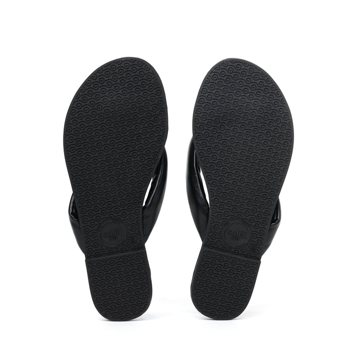 Bottom view of Gisel Noir pillow strap sandals showcasing signature wave-pattern rubber outsoles on a white background