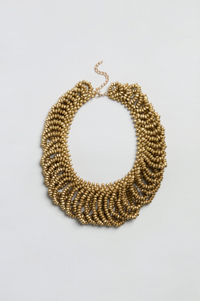Sure! Here’s the rewritten sentence using your product data: The Gold Beaded Collar Necklace features multiple rows of textured, oval-shaped gold beads and an adjustable chain clasp, beautifully showcased against a plain white background.