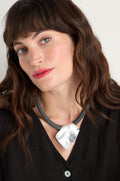 Woman with wavy brown hair wears a black top and the Hammered Silver Pendant Cord Necklace, gazing slightly to the side against a plain background.
