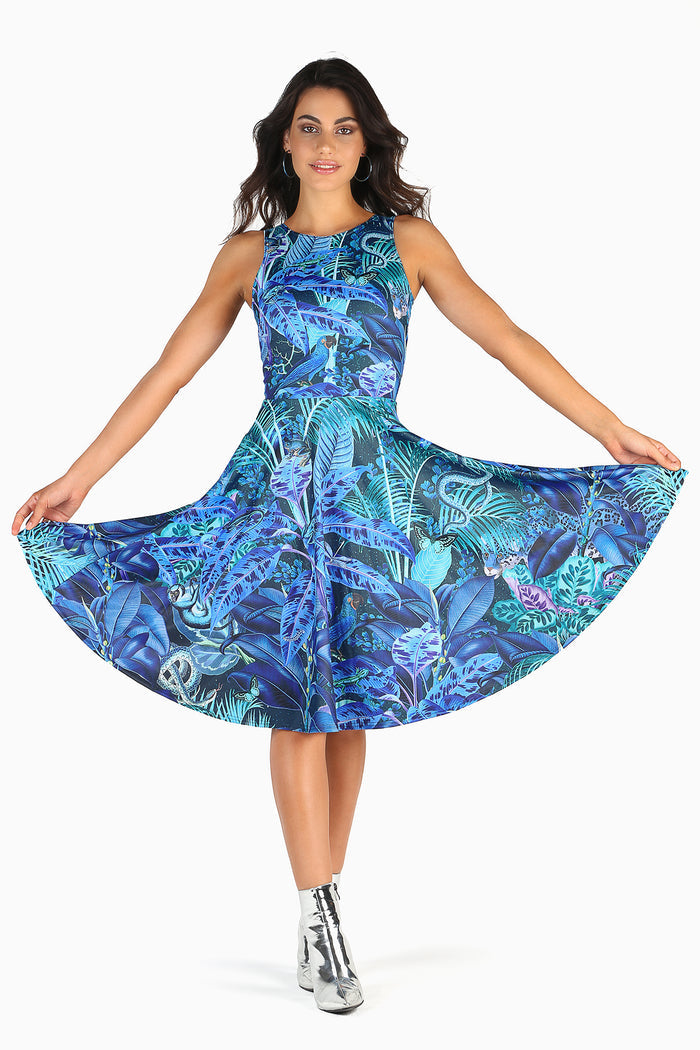 Woman wearing a dress with a blue and green jungle print featuring birds and foliage on a white background