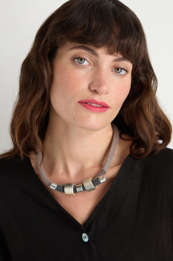 Woman with wavy brown hair wearing a black top and the Layered Marble Bead Cord Necklace, featuring chunky marble-effect beads, looking at the camera with a neutral expression.