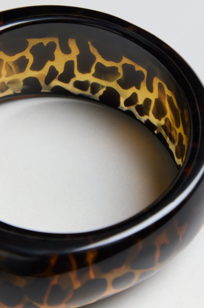 Close-up of the Leopard Bangle, featuring a round, glossy resin design with a brown and black leopard print pattern on a neutral background.