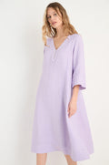 A woman in the Linen Seam Pansy Flare Dress, a light purple linen flare dress with panel seams and three-quarter sleeves, stands against a plain white background.