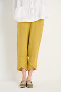 Person wearing a white textured shirt, Linen Tulip Hem Golden Bubble Trousers in mustard yellow, and brown Mary Jane shoes, standing against a plain light background.