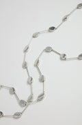 The Long Oval Disc Necklace showcases textured oval discs and slim connecting bars, elegantly displayed on a white background.
