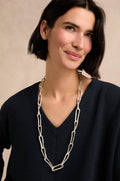 A woman with short dark hair wears a navy V-neck top and the Long Silver Links Necklace—a long, textured chain—while standing against a neutral background.