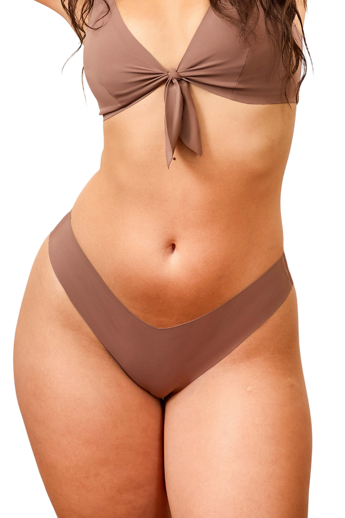 Front view of Merritt Dipped Cheeky Bikini Bottom in tan on model, showing V-shaped front and raw-cut seamless edges | alexhakim16 / M