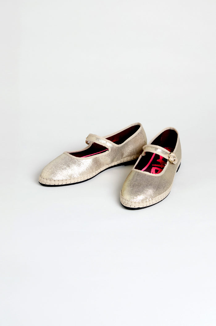 The Metallic Mary Jane Shoes feature metallic silver uppers, buckle straps, low heels, and recycled bicycle tyre soles. They are displayed on a plain white background.