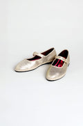 The Metallic Mary Jane Shoes feature metallic silver uppers, buckle straps, low heels, and recycled bicycle tyre soles. They are displayed on a plain white background.