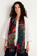 A woman stands against a plain light background, wearing a white blouse and the Painted Firework Silk Scarf, a long, lightweight accessory with an abstract print.