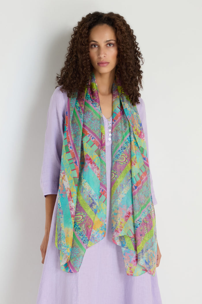 A woman wearing a light purple dress and the Archival Stripe Silk Scarf stands against a plain light background.
