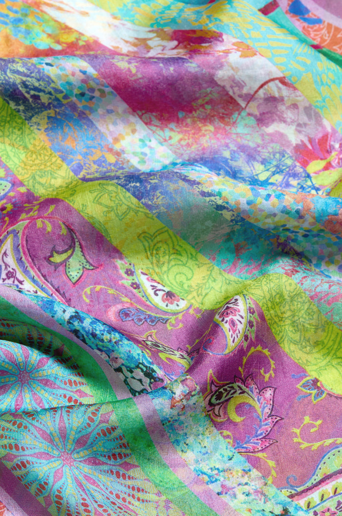 A close-up of the Archival Stripe Silk Scarf, a lightweight silk accessory with vibrant green, purple, yellow, and pink hues in floral and geometric stripe patterns.
