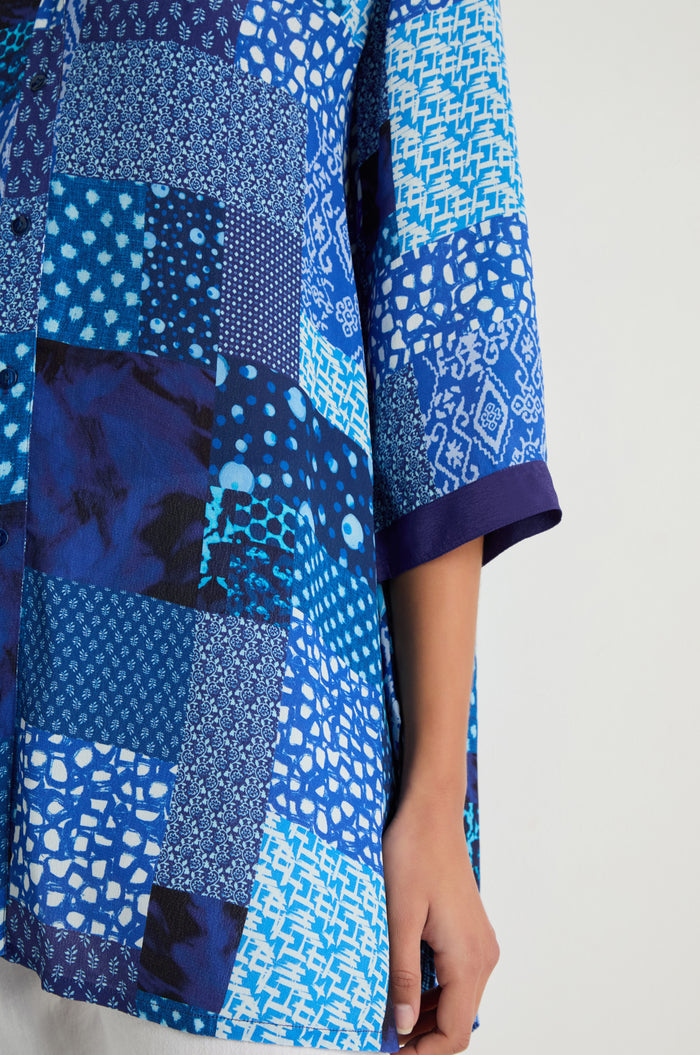 Only an arm and part of the Sahara Indigo Patchwork Longline Shirt—featuring geometric and abstract designs on soft viscose crepe—are visible.