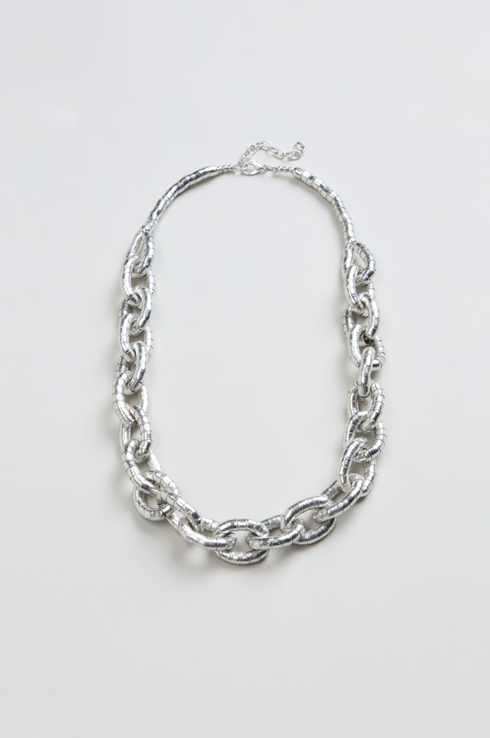 The Soft Loops Necklace, featuring large textured silver-toned oval links, is showcased on a plain light background.