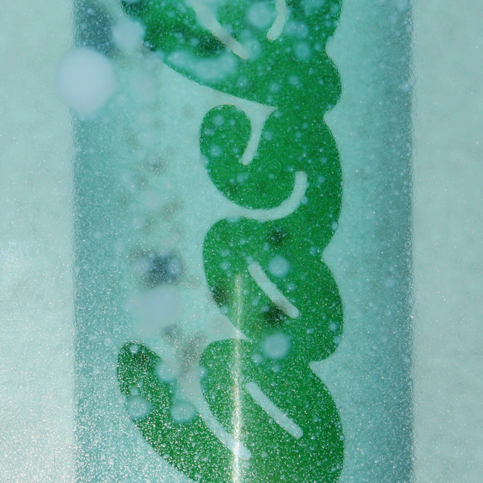 Front view of SPF 30 mineral non-aerosol spray can labeled Bask, with condensation on green can and soft blurred background