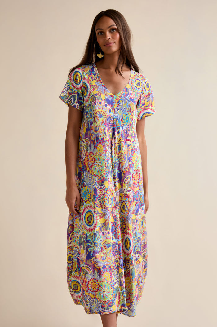 A woman faces forward wearing the Summer Sarasa Bubble Dress, an ankle-length, loose-fit style with a multicolored paisley print in silk-like viscose, set against a plain background.