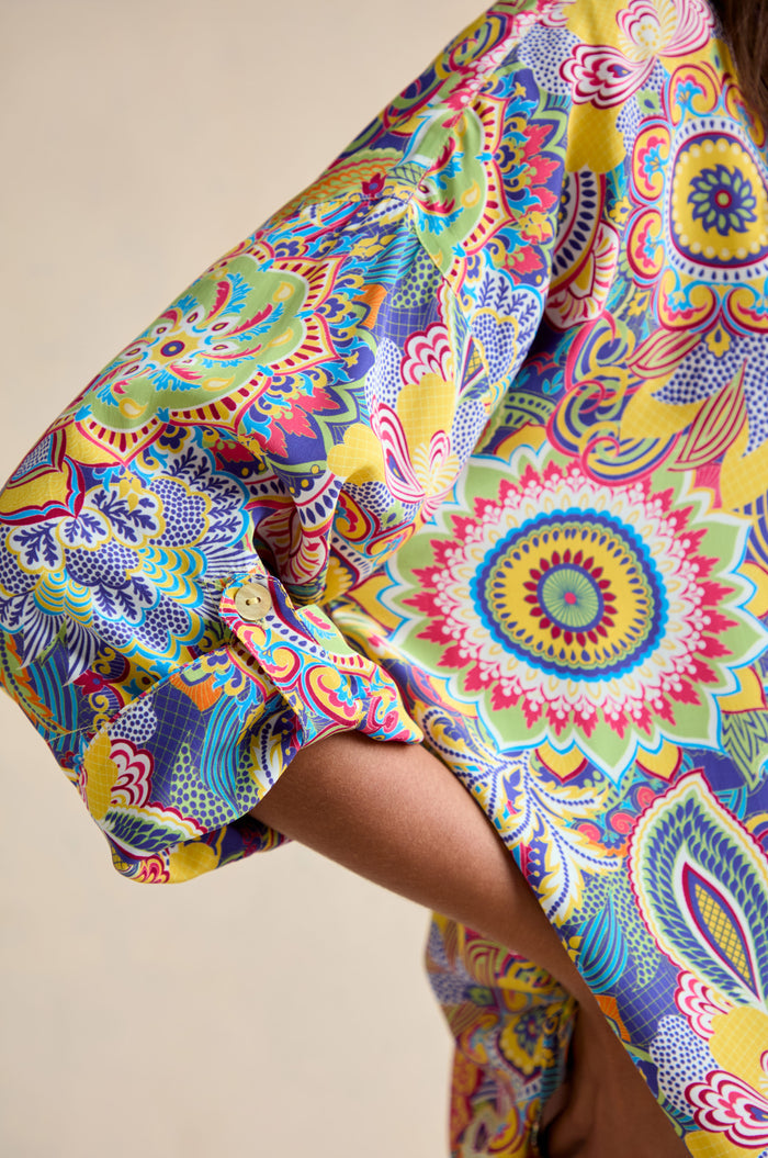 Close-up of a bent arm wearing the Summer Sarasa Relaxed Shirt, featuring a vibrant multicolored floral and geometric Sarasa print in a relaxed, boxy silhouette.