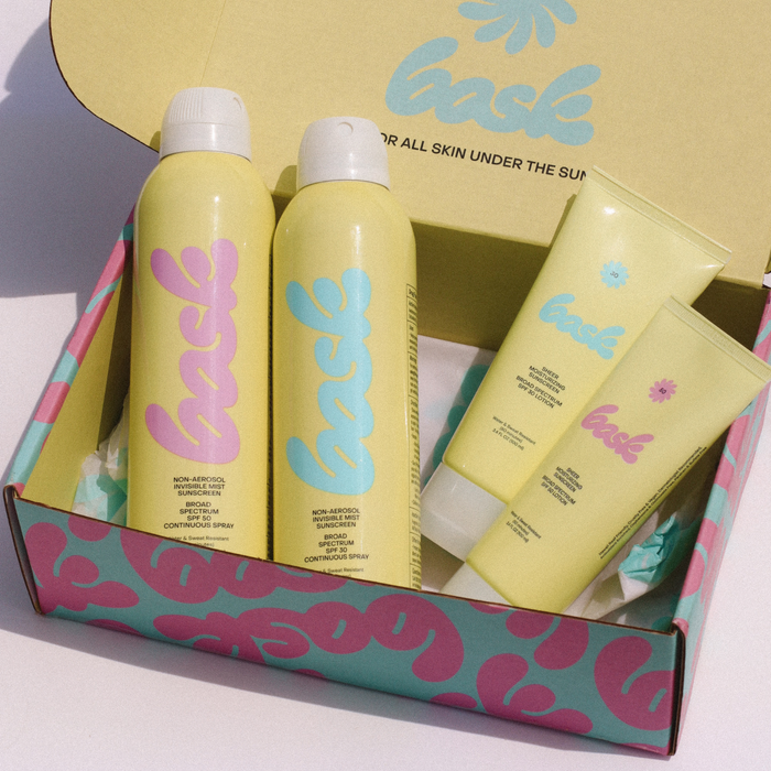 Pastel-yellow sunscreen set with blue 'bask' branding on bottles and shipping box
