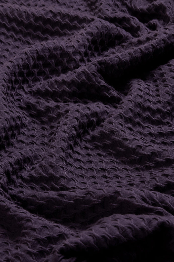 Close-up of the Waffle Textured Jersey Damson Cowl Neck Top, showcasing its deep purple hue, distinctive waffle-like texture, and softly draped folds—ideal for a chic cowl neck silhouette.