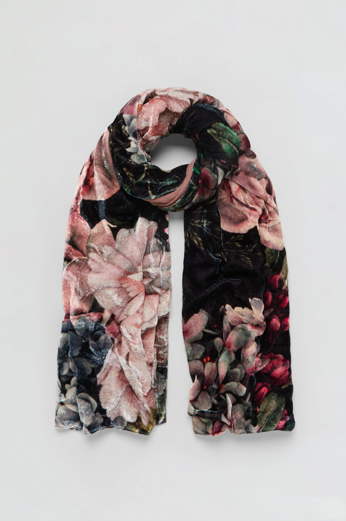 The Winter Rose Velvet Scarf, featuring a soft velvet fabric and a floral pattern in pink, green, and black hues, is displayed against a plain light background.